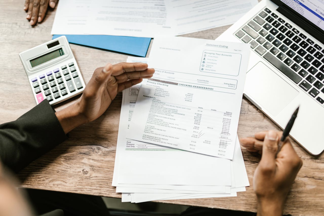 services-03 Hands holding financial documents with calculator and laptop on office desk, business analysis scene.