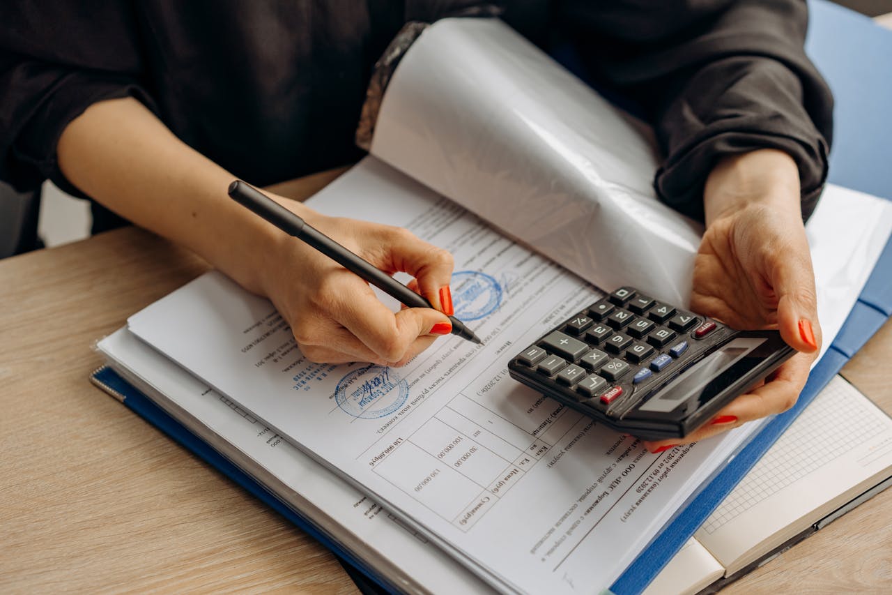 services-04 An accountant using a calculator and signing paperwork, showcasing financial analysis.