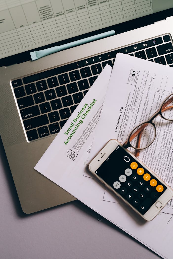 journey Small business accounting setup featuring a laptop, documents, and smartphone calculator.